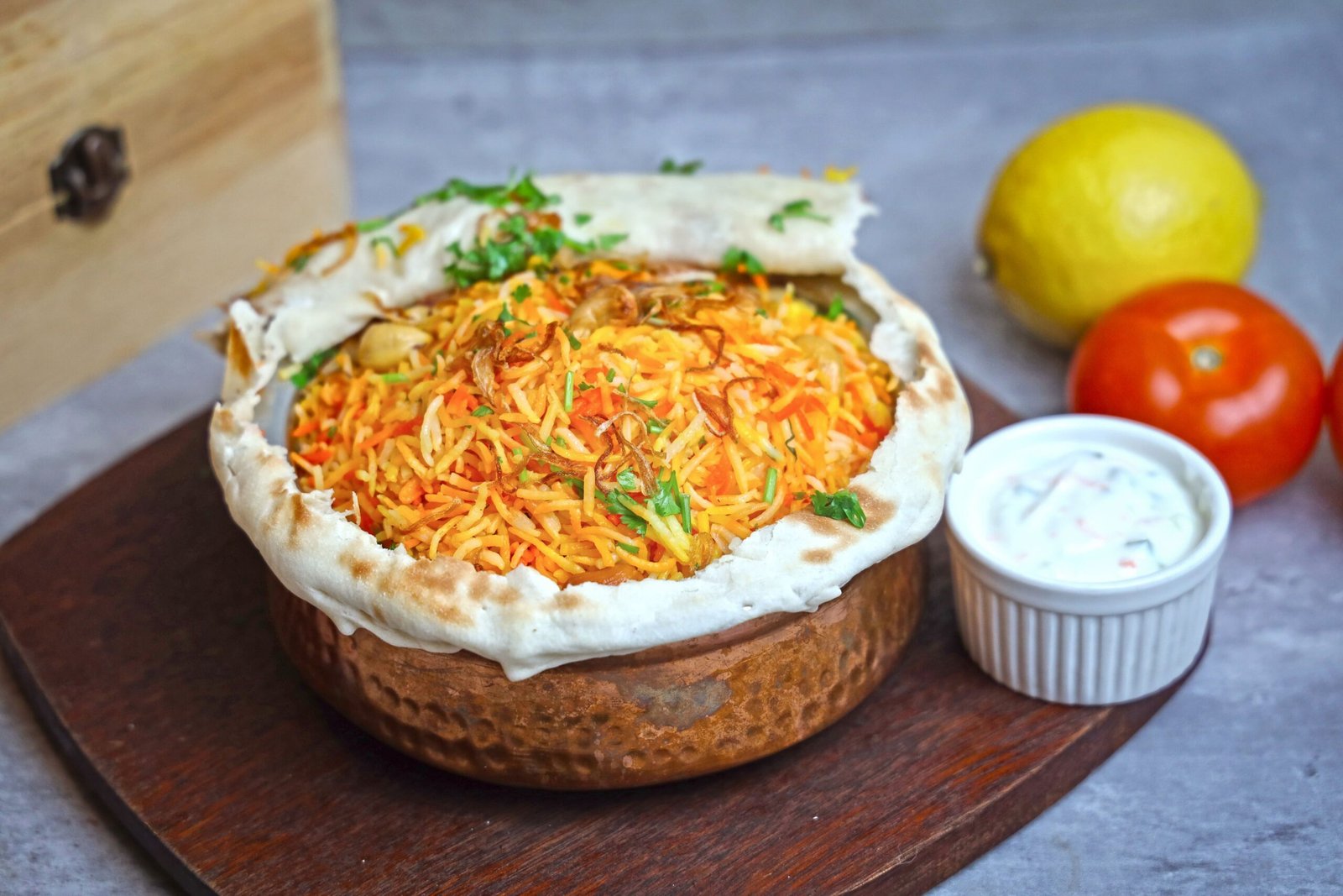 Dum Pukht Hyderabadi Biryani slow-cooked in a copper handi and sealed with dough to lock in aromas.
