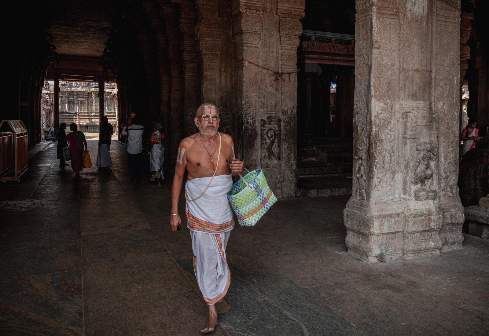 a traditional Hindu priest walking through the pillared corridors of the historic Sri Ranganathaswamy Temple in Srirangam Temple, Tiruchirappalli, Tamil Nadu, India