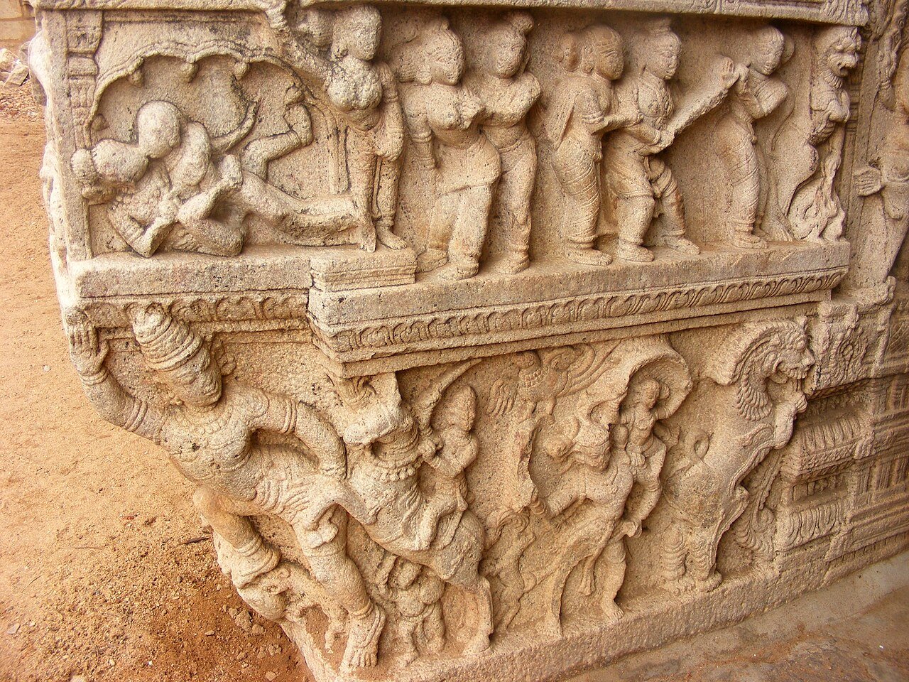 The image shows intricate stone relief carvings on a pillar or bracket in the Sesharayar Mandapam (also known as the 1000-pillar or hall area) at the famous Sri Ranganathaswamy Temple in Srirangam, Tamil Nadu, India.