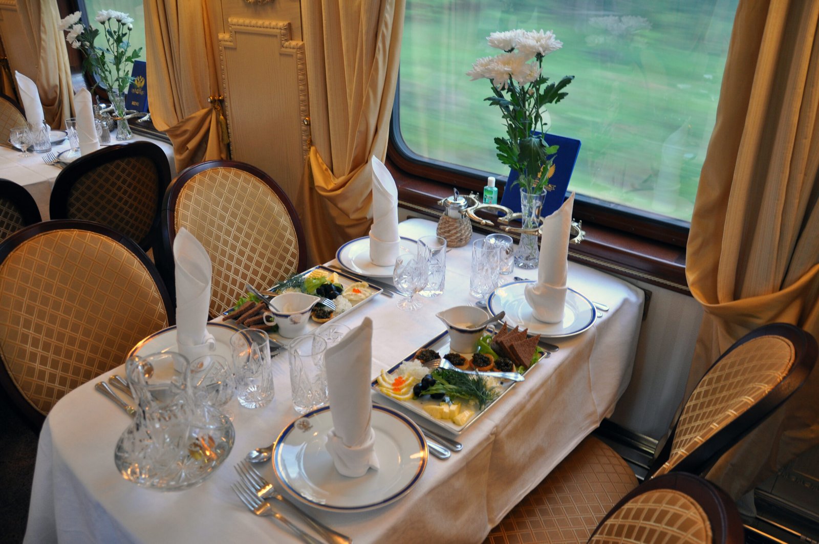 Crystal, caviar, and fresh flowers on a dining-car table set for service.