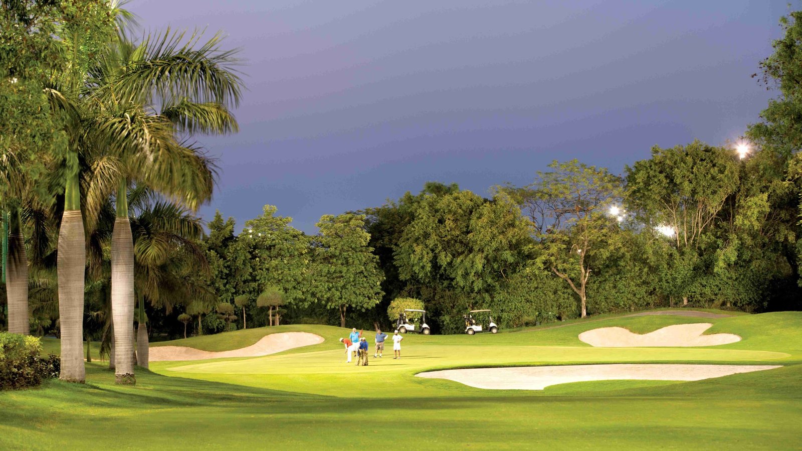 Golfers on the green at DLF Golf & Country Club, Gurugram, at dusk